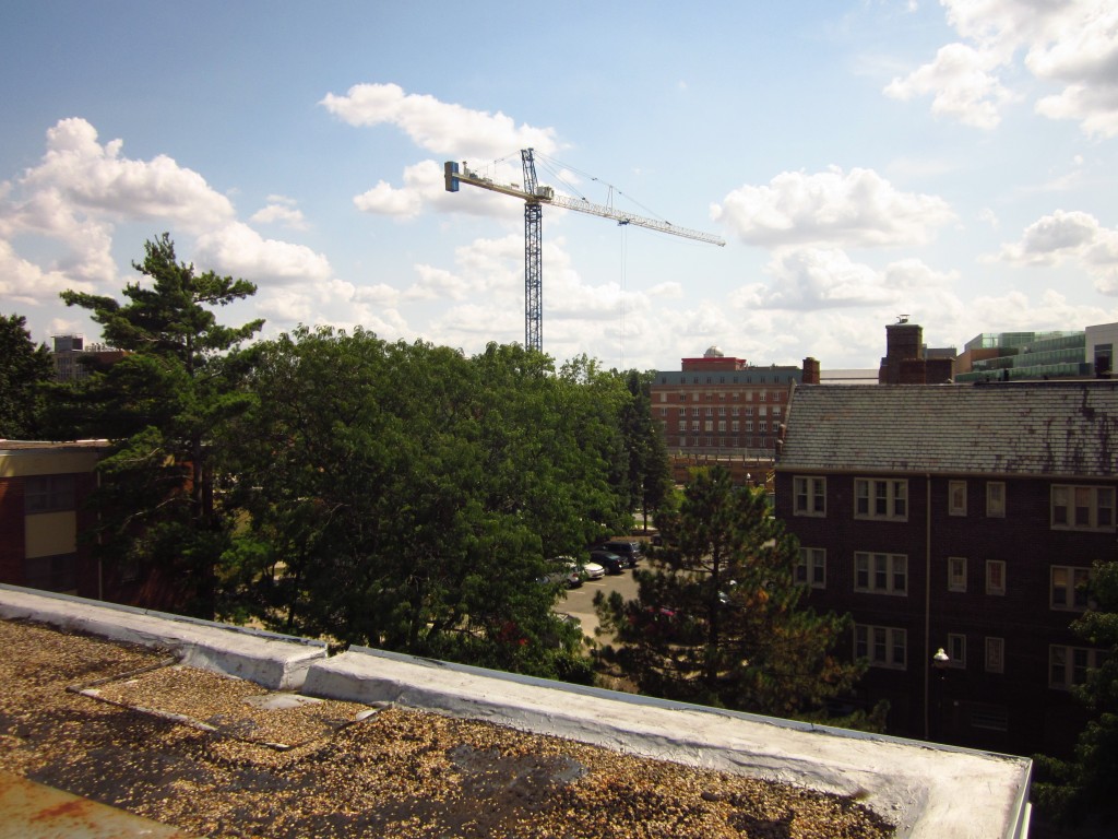 A tower crane rises over the forest of trees and low-rise buildings that makes up Ohio State University's North Campus